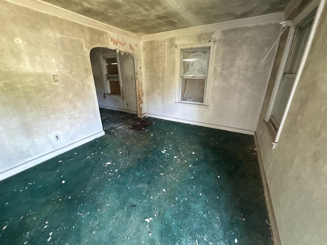 empty room with crown molding, arched walkways, and baseboards