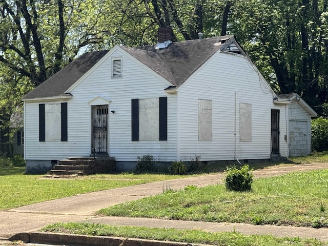 bungalow featuring roof with shingles, a chimney, and a front yard