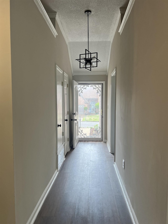doorway featuring crown molding, a textured ceiling, baseboards, and a notable chandelier