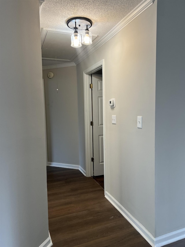 corridor featuring crown molding, wood finished floors, baseboards, attic access, and a textured ceiling