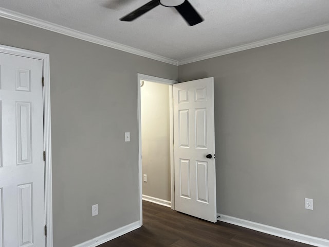unfurnished bedroom featuring dark wood-type flooring, a ceiling fan, baseboards, and crown molding