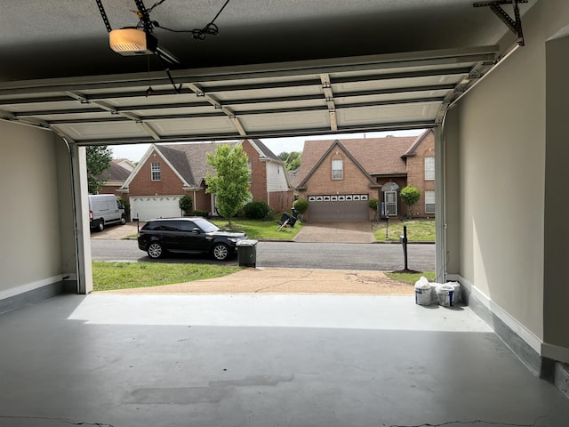 garage featuring baseboards, a garage door opener, and a residential view