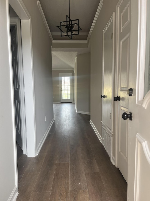 hall with crown molding, baseboards, dark wood-style flooring, and a notable chandelier