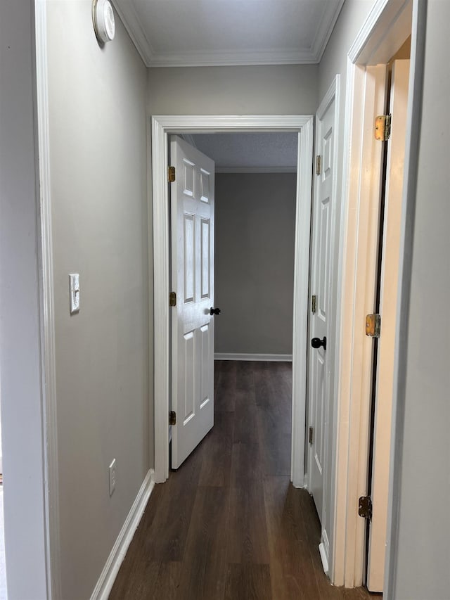 hallway featuring dark wood-style flooring, baseboards, and ornamental molding