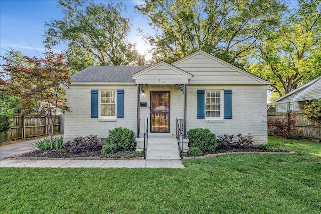 view of front of property featuring brick siding, fence, and a front yard