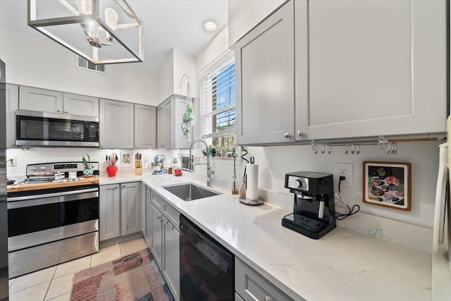 kitchen with visible vents, gray cabinets, a sink, appliances with stainless steel finishes, and light tile patterned floors
