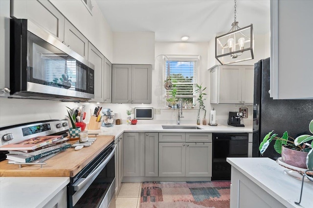 kitchen with pendant lighting, light countertops, a sink, appliances with stainless steel finishes, and gray cabinetry