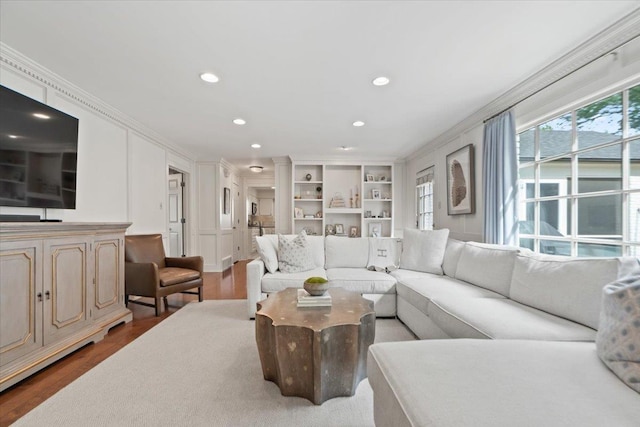 living room featuring crown molding, built in shelves, recessed lighting, and wood finished floors