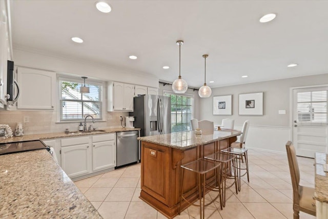 kitchen featuring a kitchen island, stainless steel appliances, light tile patterned floors, and a kitchen bar