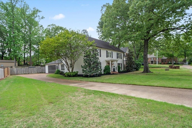colonial home with fence, driveway, and a front yard