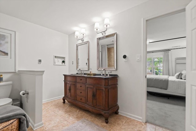 ensuite bathroom featuring double vanity, toilet, baseboards, a sink, and ensuite bath