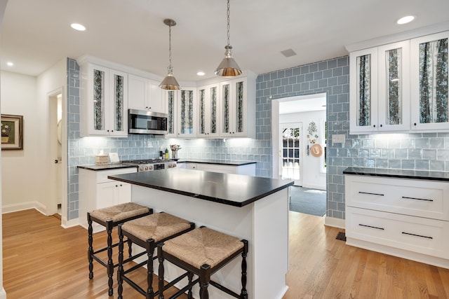 246 Palisade St, Memphis, TN 38111 - kitchen with dark countertops, decorative backsplash, stainless steel microwave, and white cabinetry