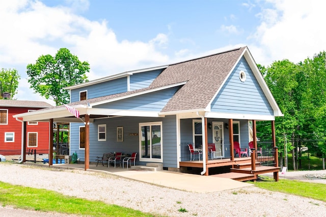 rear view of house with roof with shingles and covered porch