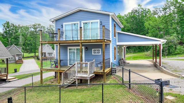 view of front of house featuring an attached carport, stairway, a front yard, a fenced backyard, and a balcony