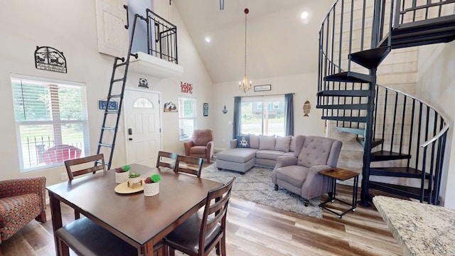 dining room with stairs, wood finished floors, a chandelier, and high vaulted ceiling
