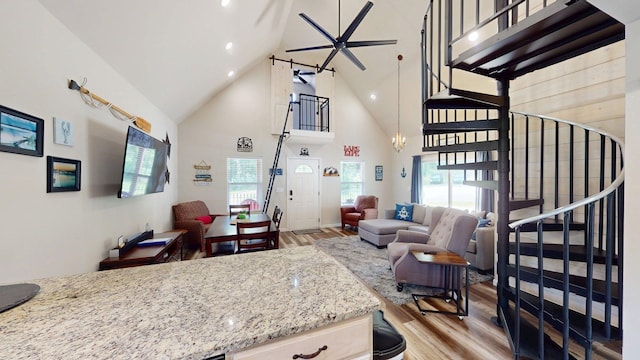 interior space featuring high vaulted ceiling, light stone counters, light wood-style flooring, and open floor plan