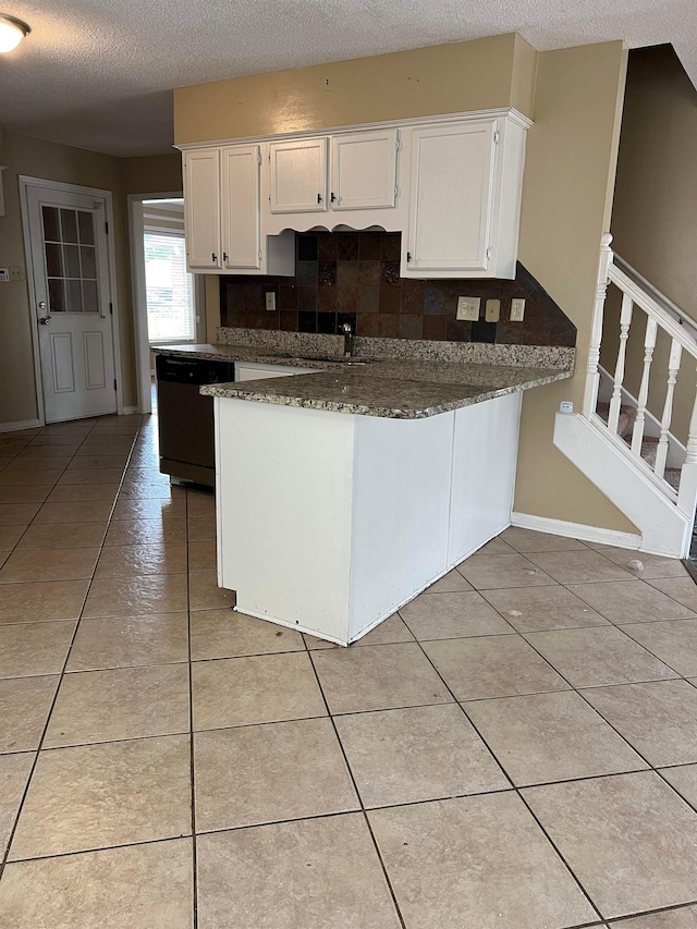 kitchen with white cabinets, a peninsula, light tile patterned flooring, and dishwasher