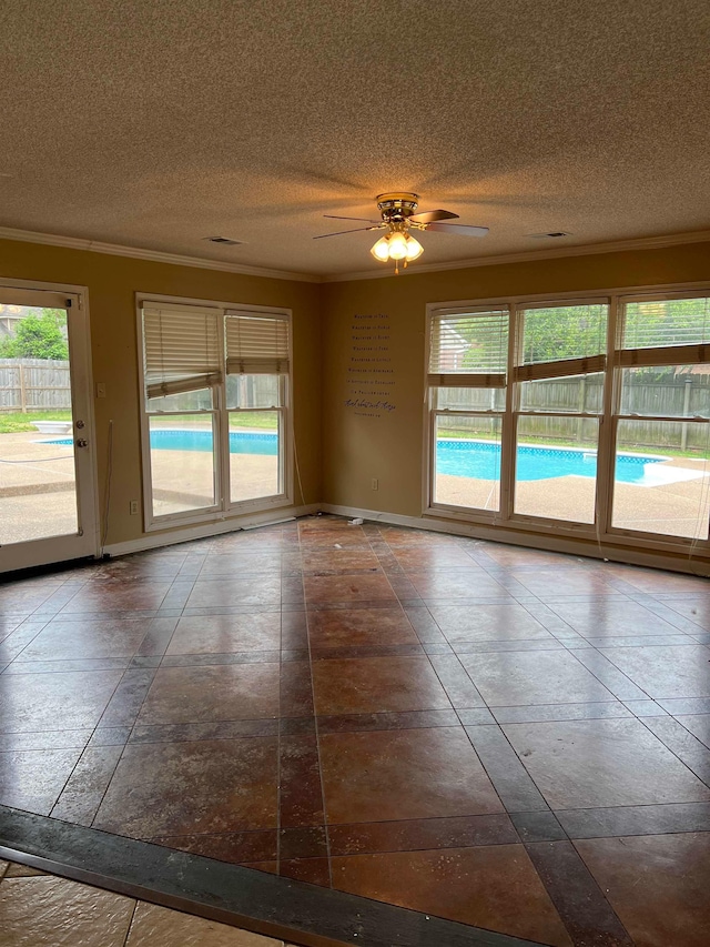 empty room with baseboards, ornamental molding, a textured ceiling, and a healthy amount of sunlight