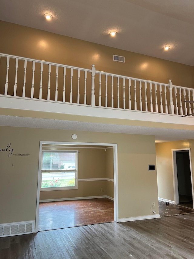 empty room with baseboards, visible vents, wood finished floors, and a high ceiling