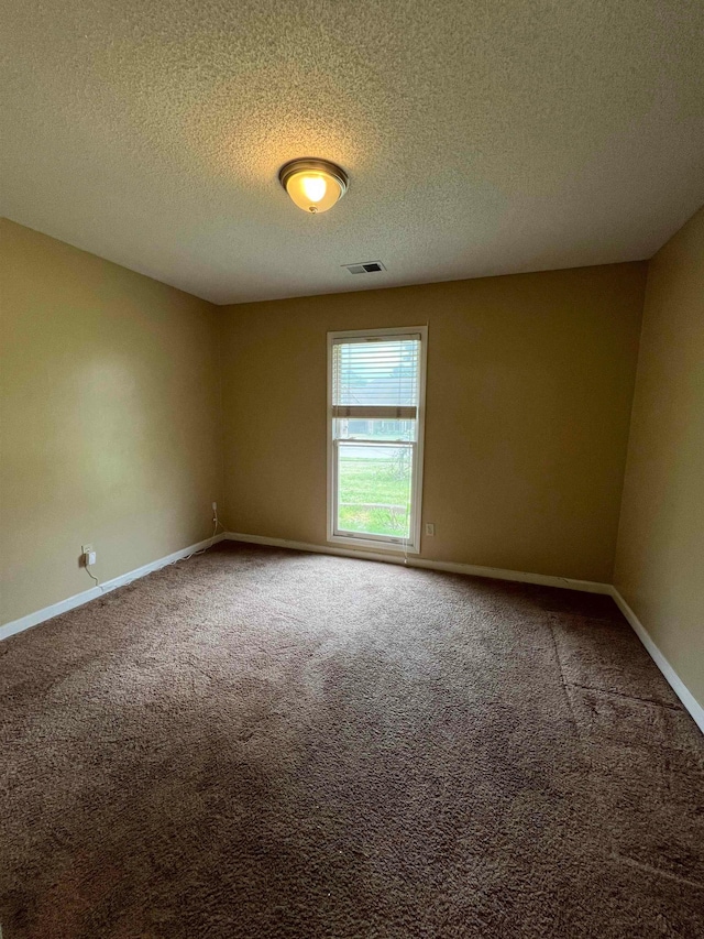 unfurnished room with carpet floors, baseboards, a textured ceiling, and visible vents