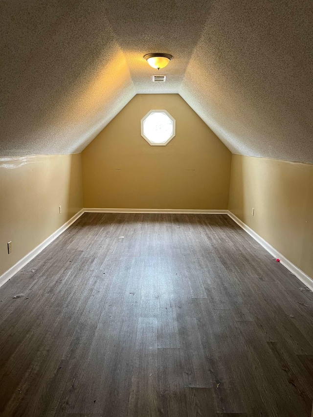 bonus room featuring baseboards, dark wood finished floors, a textured ceiling, and visible vents