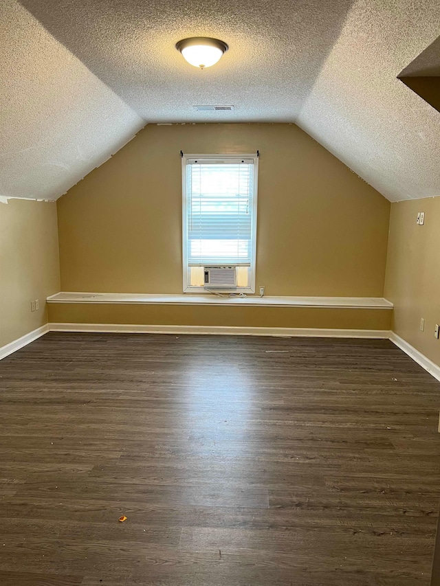 bonus room with cooling unit, a textured ceiling, baseboards, lofted ceiling, and dark wood-style floors