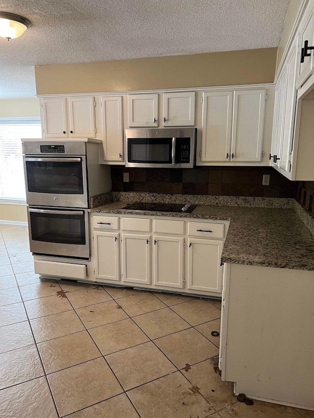 kitchen featuring a textured ceiling, light tile patterned floors, white cabinetry, and stainless steel appliances