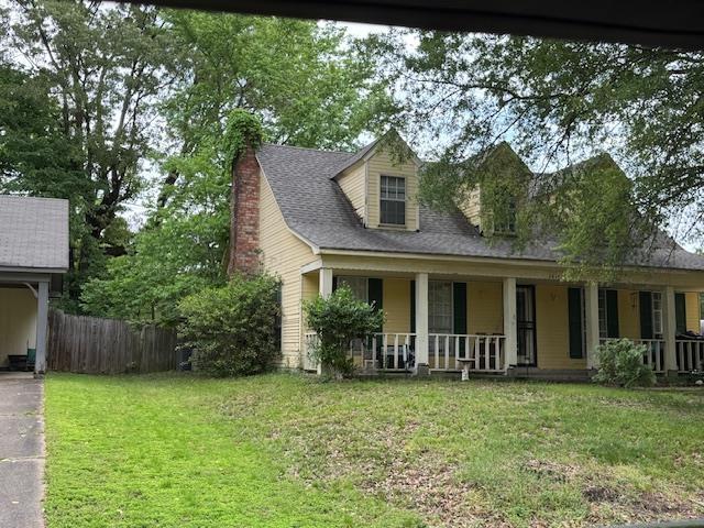 view of front of home featuring a porch, fence, a front yard, and a chimney
