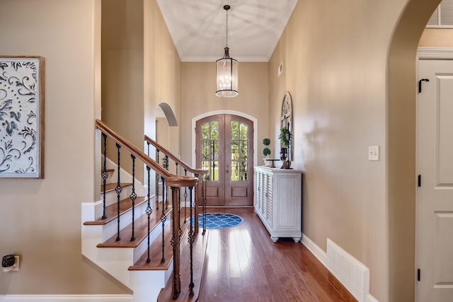 foyer entrance with arched walkways, french doors, hardwood / wood-style floors, visible vents, and stairway
