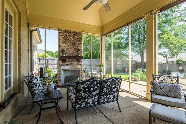 sunroom with ceiling fan and an outdoor living space with a fireplace