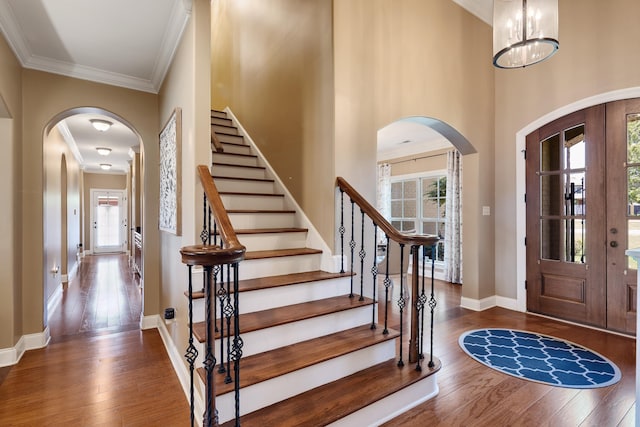 entryway with crown molding, arched walkways, hardwood / wood-style floors, and a wealth of natural light