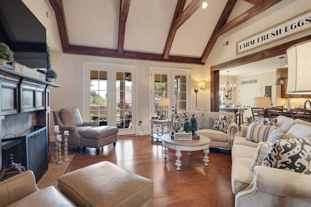 living area featuring an inviting chandelier, french doors, wood finished floors, a high end fireplace, and beamed ceiling
