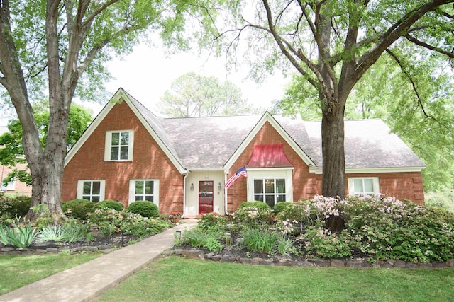view of front of home featuring brick siding, a shingled roof, and a front lawn