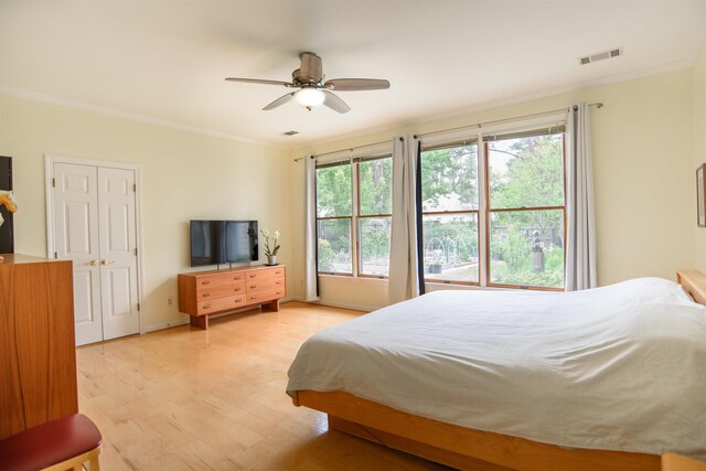 bedroom featuring visible vents, ornamental molding, multiple windows, and light wood-type flooring