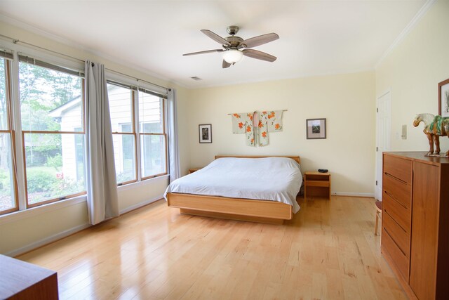 bedroom with light wood-style floors, baseboards, ornamental molding, and a ceiling fan