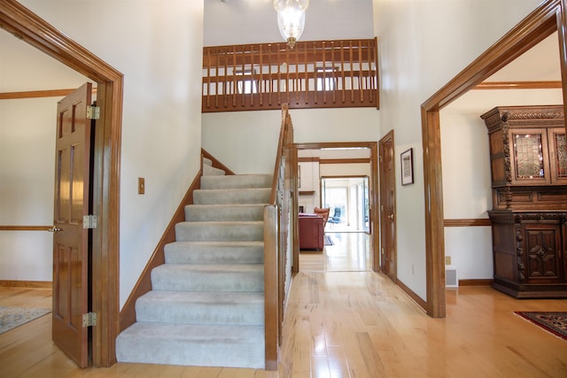 staircase featuring baseboards, a high ceiling, wood finished floors, and visible vents