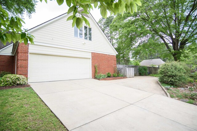 view of side of property with fence, driveway, and brick siding