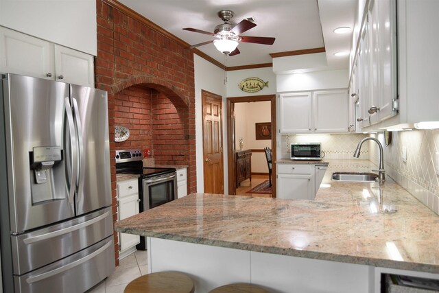 kitchen with white cabinets, a sink, stainless steel appliances, a peninsula, and backsplash
