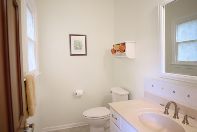 bathroom featuring vanity, tasteful backsplash, baseboards, and toilet