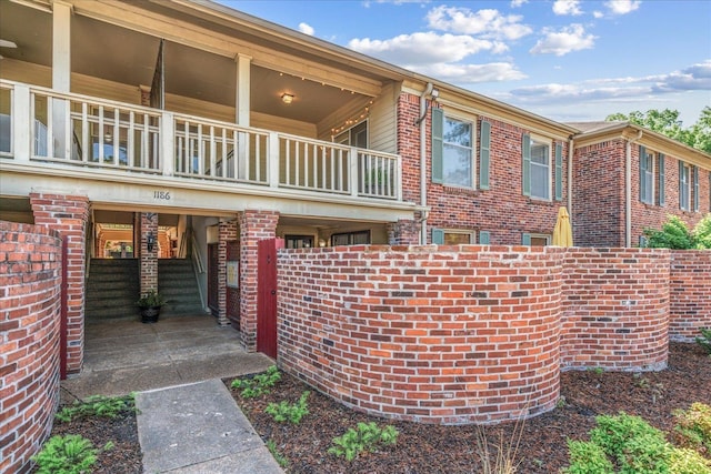 exterior space with brick siding and a balcony