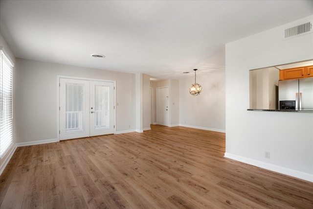 unfurnished living room with baseboards, french doors, visible vents, and light wood-style flooring