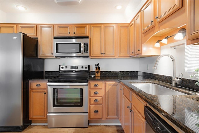 kitchen with light wood-style floors, recessed lighting, a sink, dark stone countertops, and appliances with stainless steel finishes