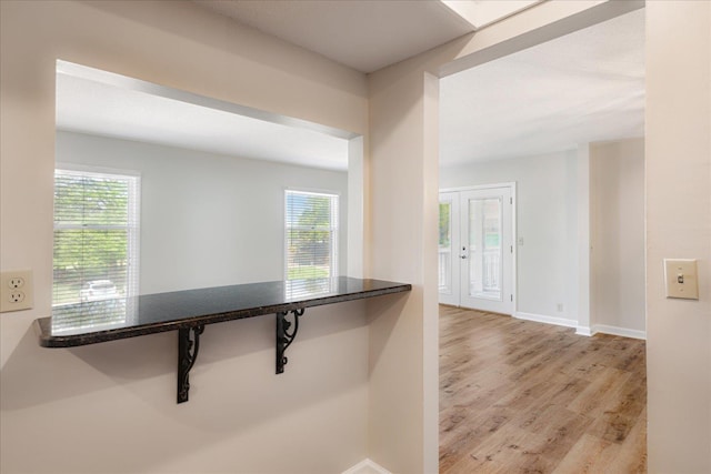 corridor with baseboards and wood finished floors