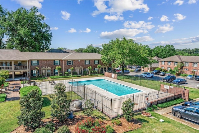 community pool featuring a yard, fence, and a residential view