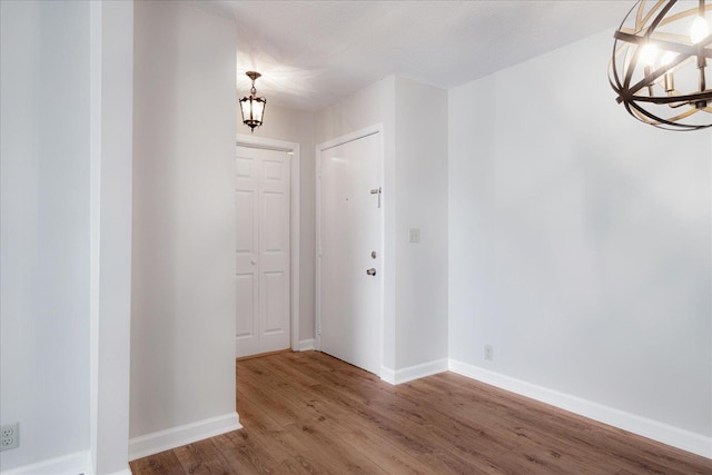 interior space featuring baseboards, wood finished floors, and a notable chandelier