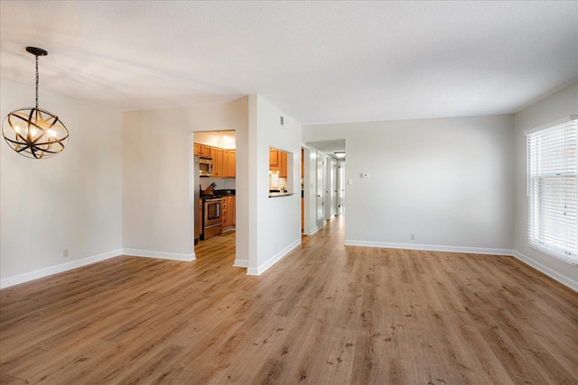 interior space featuring an inviting chandelier, light wood finished floors, and baseboards