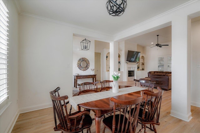 5082 Moudry Run Cv, Lakeland, TN 38002 - dining area with crown molding, a fireplace, light wood-style flooring, a ceiling fan, and baseboards