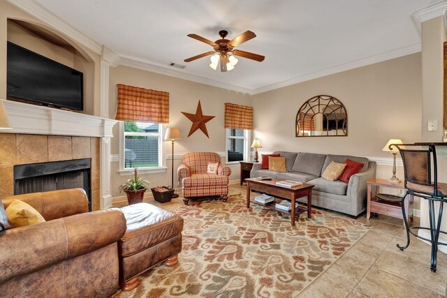 living area featuring visible vents, ornamental molding, ceiling fan, tile patterned floors, and a tile fireplace