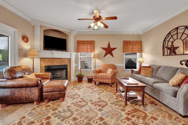 living room with crown molding, a ceiling fan, and a tile fireplace