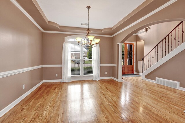 interior space featuring visible vents, arched walkways, a raised ceiling, and a chandelier